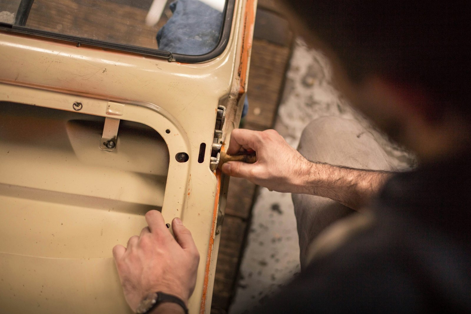 A close-up of a man repairing a car door window